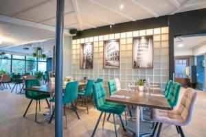 a dining room with tables and green chairs at EuroParcs Maasduinen in Belfeld