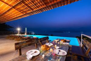 una zona de comedor al aire libre con mesas y una piscina en StayVista's Princess - A Villa with Infinity Pool & Breathtaking Views, en Lonavala