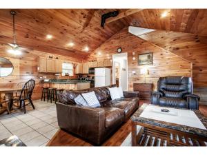ein Wohnzimmer mit einem Ledersofa und einer Küche in der Unterkunft Papa Bear - Private with Hot Tub, Pool Table, and View in Sevierville