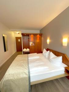 um quarto com uma cama grande com lençóis brancos e almofadas em SensCity Hotel Berlin Spandau em Berlim