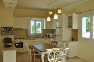 a kitchen with white cabinets and a table and chairs at Seafront Villa Kefaloniaprivatevillas in Trapezaki