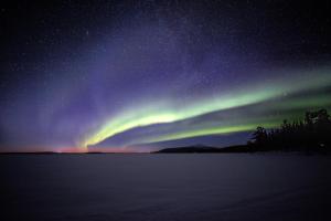an aurora in the sky over a body of water at Lapland Dream Villas in Rauhala