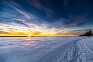 a snow covered field with the sun setting in the background at Lapland Dream Villas in Rauhala