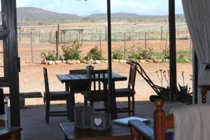 a table and chairs with a view of a field at PurePlaas Self catering Volmoed Oudtshoorn Klein Karoo in Oudtshoorn