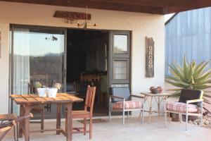 eine Terrasse mit einem Holztisch, Stühlen und einem Tisch in der Unterkunft PurePlaas Self catering Volmoed Oudtshoorn Klein Karoo in Oudtshoorn