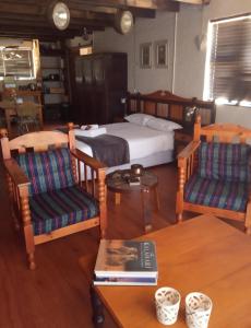 um quarto com uma cama, 2 cadeiras e uma mesa em PurePlaas Self catering Volmoed Oudtshoorn Klein Karoo em Oudtshoorn