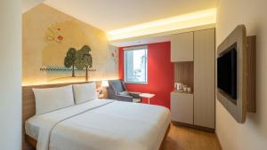 a hotel room with a white bed and a tv at ibis Mumbai Airport - An Accor Brand in Mumbai