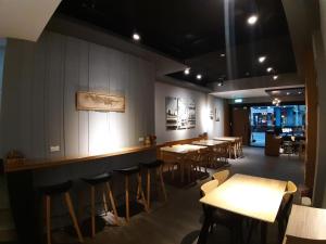 a restaurant with wooden tables and chairs and a bar at 藏青民宿The Wind Guesthouse-Youth inn in Tainan