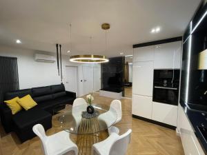 a living room with a glass table and white chairs at Prestige Line Manhattan in Legnica