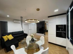 a living room with a glass table and a black couch at Apartamenty Manhattan in Legnica