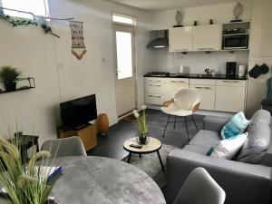 uma sala de estar com um sofá e uma mesa em Sommerhaus Glücklich am Meer 2 mit Wellnesszugang em Egmond aan Zee