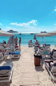 een groep mensen op een strand met stoelen en parasols bij Acrogiali Beachfront Hotel Mykonos in Platis Yialos Mykonos