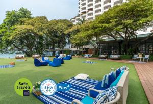 a large lawn with blue chairs on it at Cosy Beach Hotel - SHA Extra Plus in Pattaya South