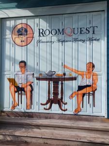 zwei Männer sitzen an einem Tisch im Fenster in der Unterkunft RoomQuest Rimrabeang at Amphawa in Amphawa
