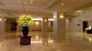 a lobby with a vase with yellow flowers in it at Hotel Grand Hill Ichigaya in Tokyo