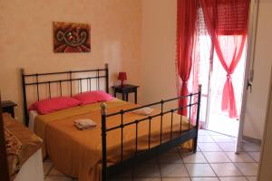 a bedroom with a bed with orange sheets and red pillows at Casevacanza Soleluna in Alcamo Marina
