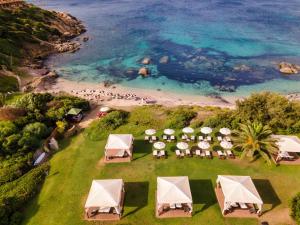 uma vista sobre uma praia com mesas e cadeiras em Hotel Cala Caterina em Villasimius