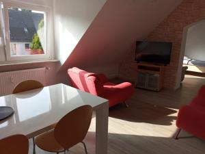 a living room with red chairs and a television at Monteurzimmer/Ferienwohnung Bottrop in Bottrop