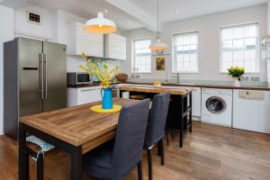 a kitchen with a wooden table with chairs and a refrigerator at Veeve - Wimbledon Wildflower in London