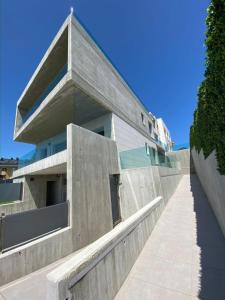 un gran edificio de hormigón con una acera delante de él en Apartamentos modernos Residencial el Pinar, en Liencres