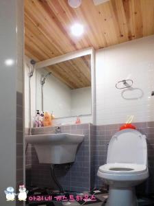 a bathroom with a sink and a toilet with a mirror at Ariene Guesthouse in Gwangju