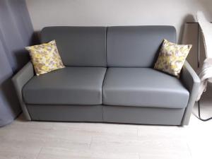 ein graues Sofa mit zwei Kissen im Wohnzimmer in der Unterkunft Jolie studio au coeur d'Allos in Allos
