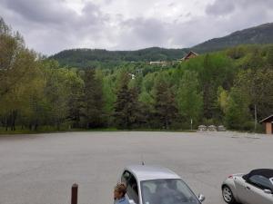 Eine Frau steht neben einem Auto auf einem Parkplatz. in der Unterkunft Jolie studio au coeur d'Allos in Allos