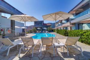 un patio con sedie e ombrelloni accanto alla piscina di Theros Villas & Suites a Chrisi Ammoudia