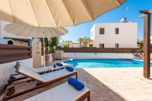 阿依納帕的住宿－Villa Poseidon by Ezoria Villas，一个带游泳池、椅子和遮阳伞的庭院