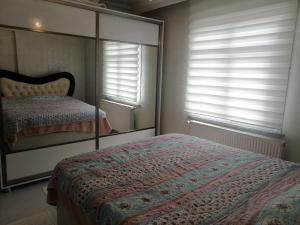 Schlafzimmer mit einem Bett, einem Spiegel und Fenstern in der Unterkunft Rahat ve sakin ev in Istanbul