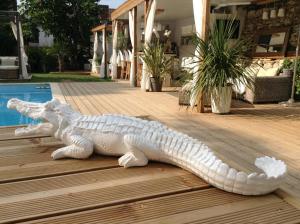 a statue of a alligator laying on a wooden deck at Buddha Beach Thoiry in Thoiry