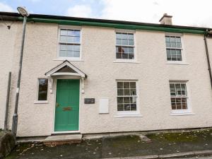 a white brick house with a green door at Bridgend Cottages in Llandrindod Wells