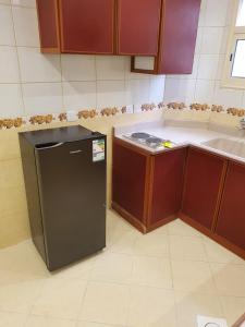 a kitchen with a black refrigerator and a sink at Ahla Taif Apartments in Abha