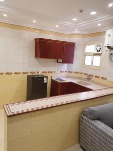 a kitchen with brown cabinets and a black refrigerator at Ahla Taif Apartments in Abha
