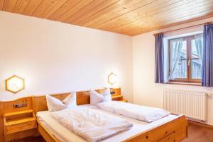 a bedroom with a bed with white sheets and a window at Ferienwohnung Guffertblick in Jachenau
