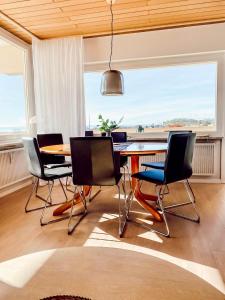 una sala da pranzo con tavolo, sedie e una grande finestra di Ferienwohnung - Schöne Aussicht a Immenstaad am Bodensee