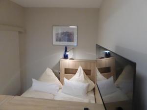 um quarto com uma cama com almofadas brancas e um espelho em Studio Apartment 2 em Tübingen