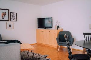- un salon avec une télévision, une table et des chaises dans l'établissement Apartment Mohnenfluh, à Schröcken