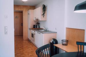 une cuisine avec des placards blancs, une table et un comptoir dans l'établissement Apartment Mohnenfluh, à Schröcken