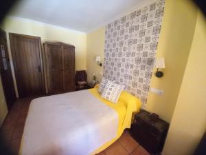 a bedroom with a white bed with a yellow blanket at Posada de Campillo in Campillo de Altobuey