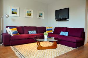 Una sala de estar con un sofá morado y una mesa. en Le Mont-Royal Sky by HomeInMontreal, en Montreal
