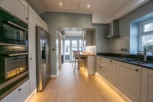 a kitchen with white cabinets and a table in it at Mairannedd in Abersoch