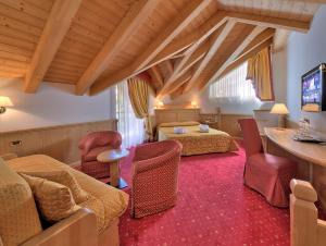 una camera d'albergo con due letti e un soggiorno di Sporthotel Rosatti a Dimaro