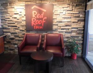 
a red chair sitting in front of a red wall at Red Roof Inn Cleveland - Medina in Medina

