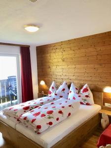 a bedroom with a large bed with red and white pillows at Pension Heidelberg - Fam Fuchs in Hopfgarten im Brixental