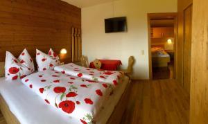 um quarto com uma cama com flores vermelhas em Pension Heidelberg - Fam Fuchs em Hopfgarten im Brixental