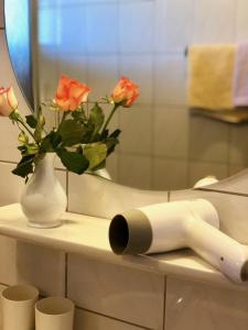 baño con jarrón de rosas y espejo en Pension Heidelberg - Fam Fuchs, en Hopfgarten im Brixental