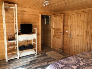 a bedroom with a bed and a tv in a wooden cabin at Chalet de La Source in Rognac