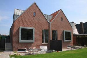 una casa de ladrillo con mesas y sillas delante de ella en Sommerloft Norderney Ferienhaus en Norderney