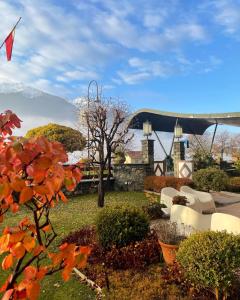 un giardino con sedie bianche e montagne sullo sfondo di Paradise Hotel & Wellness a Saint Vincent